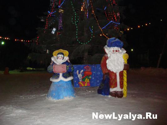 Фигурки снегурочки и деда мороза у елки на городской площади